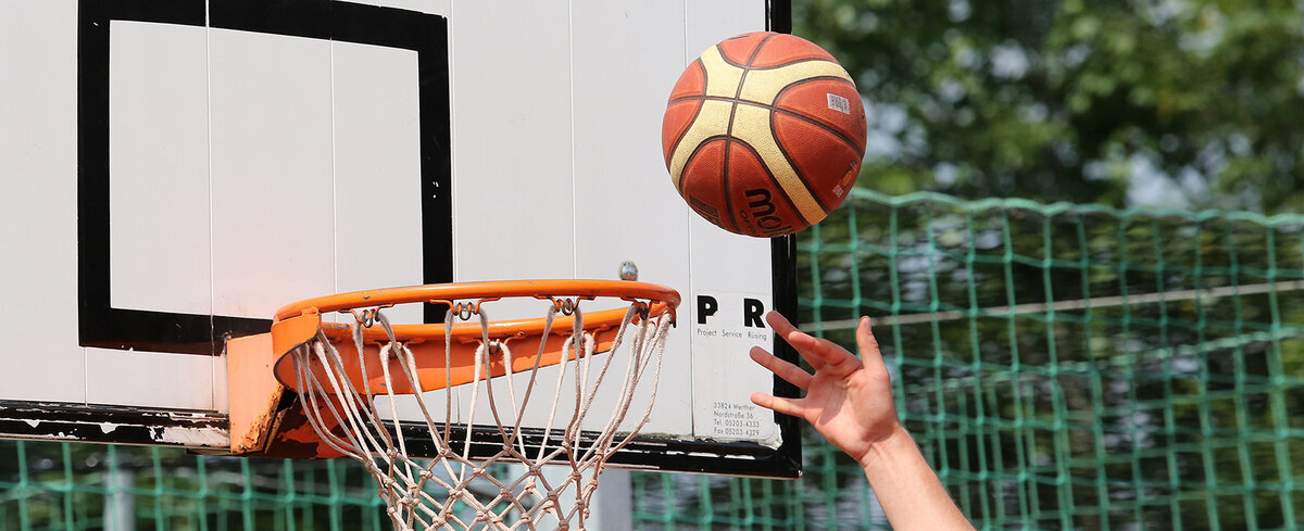 A basketball is hitting the basketball goal