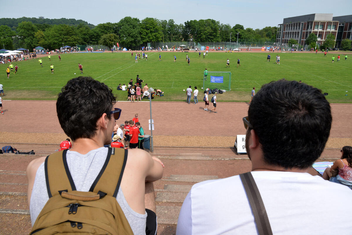 Zwei Menschen auf einer Tribüne mit Blick auf eine Wiese
