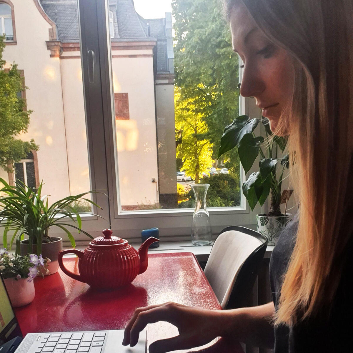 Frau an ihrem Laptop sitzt vor einem Fenster