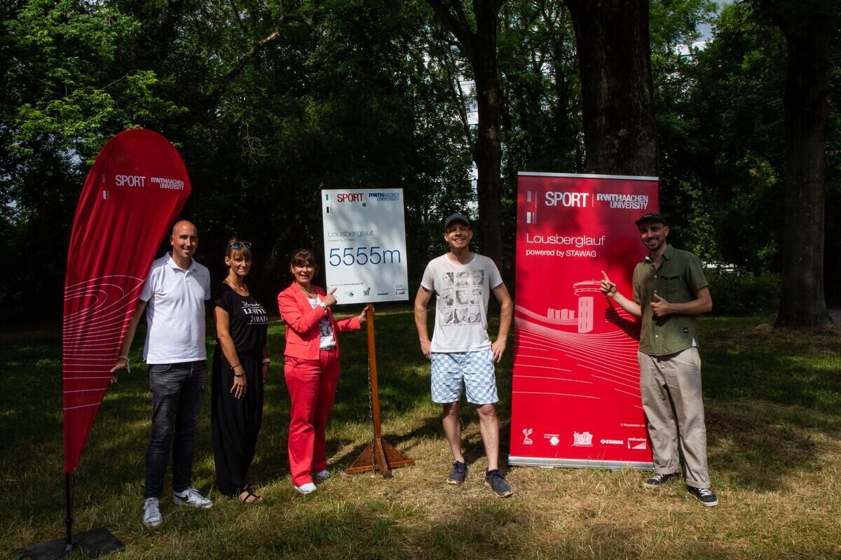Projektteam posiert vor Lousberglauf Fahnen