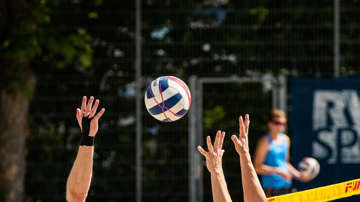 Hände, die nach einem Beachvolleyball greifen