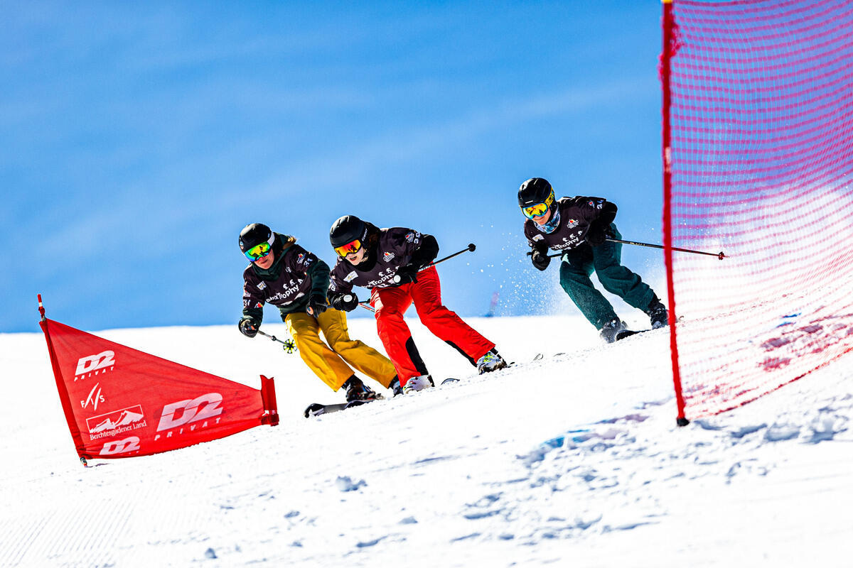 Drei Skifahrende fahren bergab